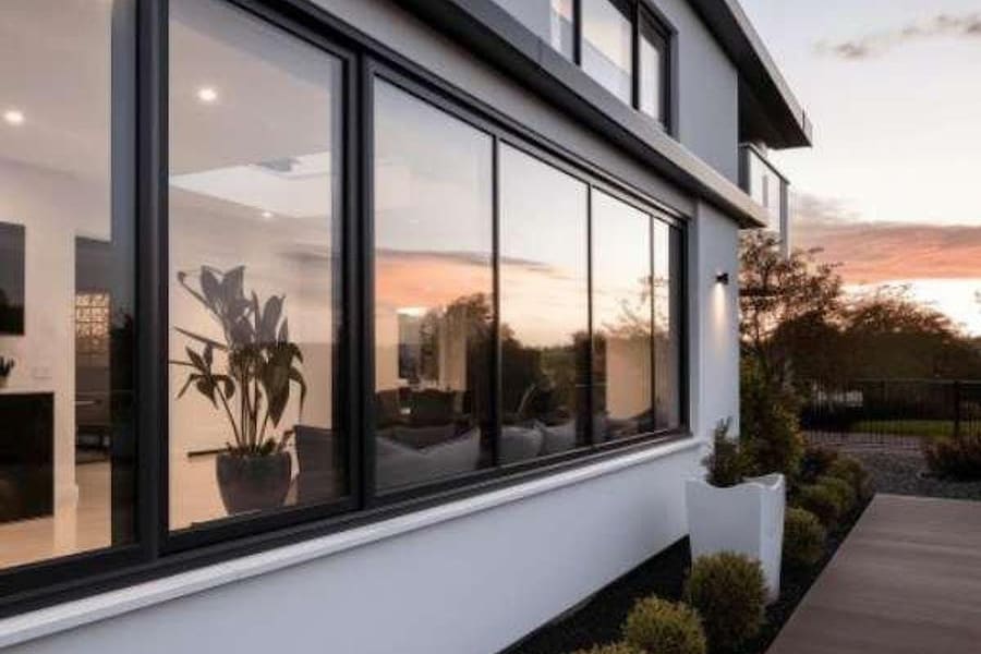 Black-framed aluminium windows on a modern home lit from inside at dusk