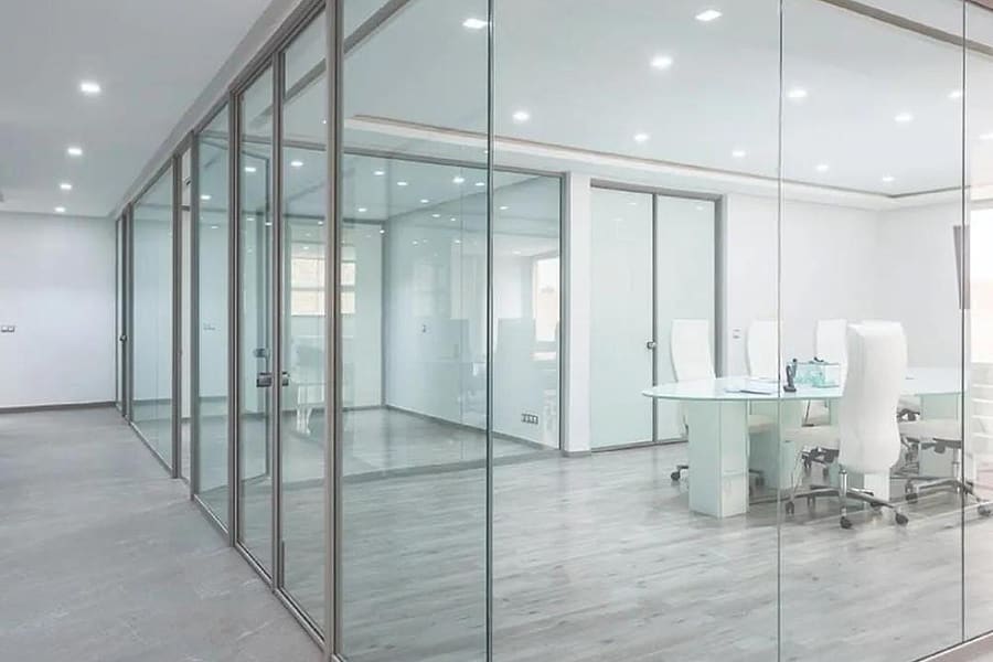 Modern office interior divided by floor-to-ceiling glass partitions with slim aluminium frames